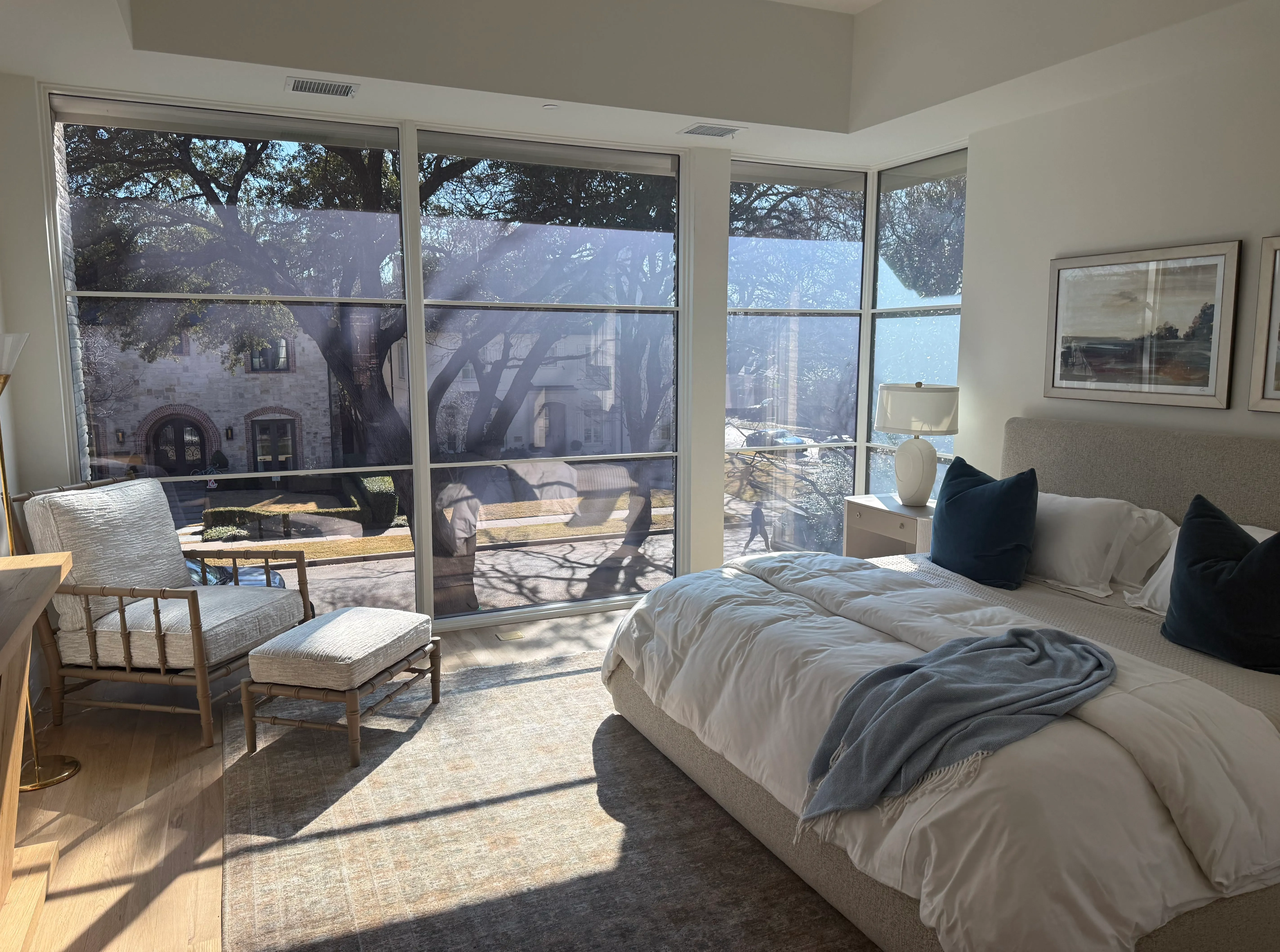 Primary bedroom with a floor-to-ceiling Revive smart glass window wall in its clear state, looking out to the street